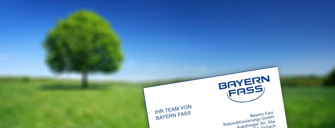 eine weiße Visitenkarte von Bayern-Fass vor einem grünen Baum auf einer grünen Wiese und blauem Himmel