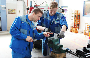 Ein Bayern-Fass-Kollege zeigt einem jungen Kollegen einen Arbeitsschritt im Anlagenbau 